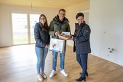 Tamara Schulz und Benjamin Palgetshofer erhalten von Evelyn Sierninger (rechts, Alpenland) einen Korb mit Brot und Salz als Willkommensgeschenk zur neuen Wohnung.